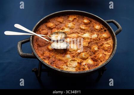 Eine große Pfanne Shakshouka, ein beliebtes maghrebinisches Gericht im Nahen Osten und in Israel, bestehend aus Eiern, pochiert in einer Tomatensoße, Olivenöl und pepp Stockfoto