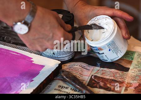 Würzburg, Deutschland, 30. Januar 2025. Künstler, der mit einem Palettenmesser weiße Linolfarbe der Marke College Linol schöpft Stockfoto