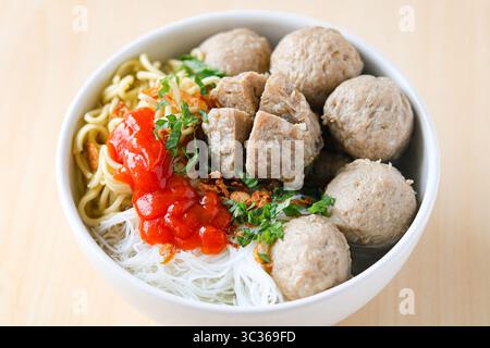Aus nächster Nähe sehen Sie Bakso (auch bekannt als Baso), eine beliebte Fleischbällchensuppe. Die Brühe ist mit Rindfleischbällchen, gelben Nudeln, Vermicelli und Chili gefüllt. Stockfoto