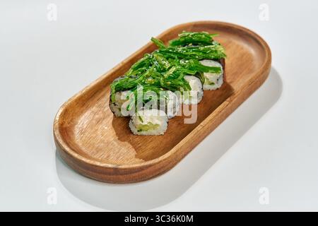Eine köstliche Sushi-Portion aus frischen Zutaten, mit Reisrollen mit lebendigem Algen auf einer Holzplatte, die perfekt zum Genießen geeignet ist Stockfoto