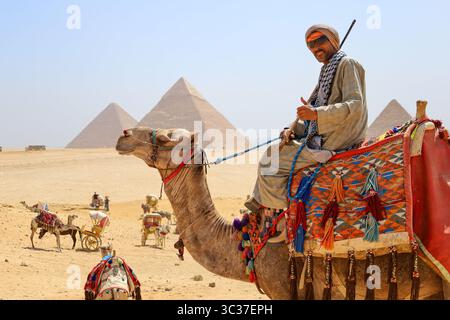 Gizeh, Ägypten, 17. Juli 2025: Ein Tourist, der auf einem Kamel vor den Pyramiden von Gizeh in der Nähe von Kairo reitet Stockfoto