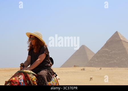 Gizeh, Ägypten, 17. Juli 2025: Ein Tourist, der auf einem Kamel vor den Pyramiden von Gizeh in der Nähe von Kairo reitet Stockfoto