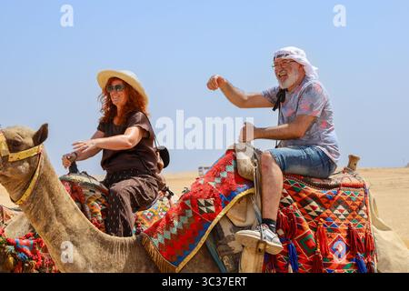 Gizeh, Ägypten, 17. Juli 2025: Ein Tourist, der auf einem Kamel vor den Pyramiden von Gizeh in der Nähe von Kairo reitet Stockfoto