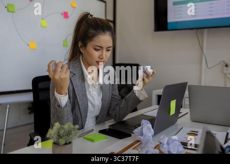 Geschäftsmann ist aufgrund von Überlastung gestresst, ein Mitarbeiter des Unternehmens ist aufgrund der Frist sehr müde und zeigt Anzeichen von Ermüdung und Stress im of Stockfoto