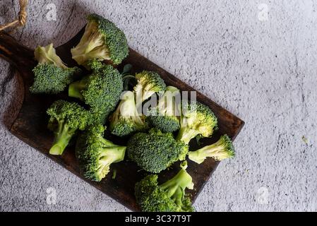 Eine lebendige Präsentation frisch geernteter Brokkoli-Röschen auf einem rustikalen Schneidebrett, inspiriert für kreative Kochideen oder gesunde Speisen Stockfoto