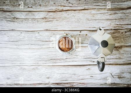 Minimalistisch flache Mokakanne und frisch gemahlenen Kaffee auf hellem, aufbereitetem Holz, viel Platz für das Café-Branding oder Social-Media-Banner Stockfoto