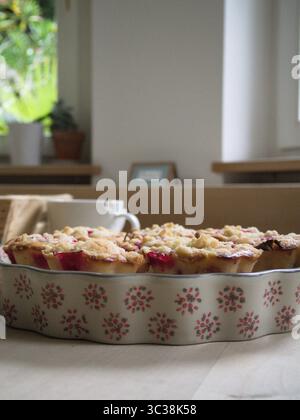 Beeren-Muffin und Blumenkeramik mit Teetasse, gemütliche und nostalgische hausgemachte Szene. Stockfoto