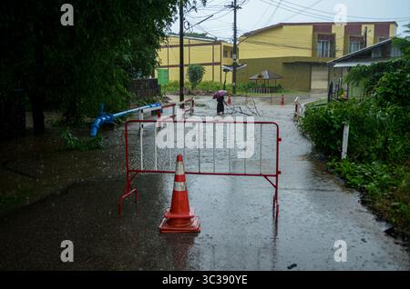 Ein Bewohner räumt schwimmende Äste von einer Straße ab, die gesperrt wurde, nachdem ein Bach seine Ufer in Mae SOT, Thailand überschwemmte. Starke Regenfälle durch den schweren Tropensturm Wipha verursachten Ende Juli 2025 weitverbreitete und schwere Überschwemmungen in Nordthailand, wobei das Ereignis für einige Provinzen als das schlimmste seit Jahrzehnten beschrieben wurde. In Gebieten wie Mae SOT in der Provinz Tak verursachte der anhaltende Regen örtliche Ströme über- und untertauchten Straßen. Die Situation wurde viel ernster, als der Moei River (auch bekannt als Thaungyin River), der die Grenze zwischen Thailand und Myanmar bildet, zum Drang kam Stockfoto