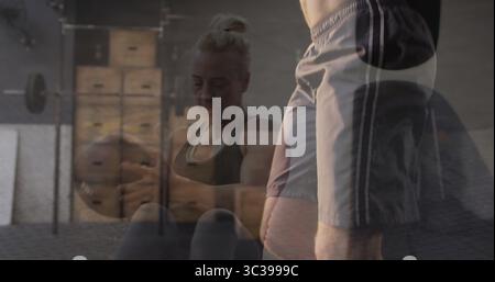 Durchführung gewichteter Sit-ups Frau in Sportbekleidung, die Medizinball auf Turnmatte von Plyoboxen hält Stockfoto