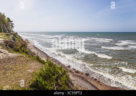 Dramatische Ostsee-Klippenküste mit schaumigen Wellen und blauem Himmel Stockfoto