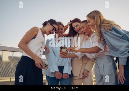 Freunde teilen fröhlich Momente im Freien mit dem Smartphone, genießen das Leben und die anderen zusammen Stockfoto