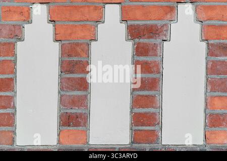 Nahaufnahme einer historischen Backsteinfassade mit drei vertikalen Putzeinlagen in einem sich wiederholenden Muster. Stockfoto
