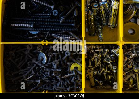 Verschiedene Schrauben und Befestigungselemente in gelbem Organizer Box Stockfoto