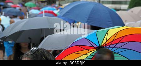 Regenbogenfarben im Vordergrund dominieren den Panoramablick auf farbenfrohe Regenschirme im Regen in der Fußgängerzone im Zentrum von Florenz, Italien Stockfoto