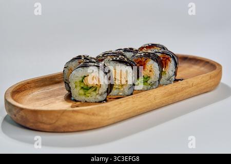 Köstliche Sushi-Platte mit frisch gerolltem Sushi mit bunten Zutaten auf einem wunderschönen hölzernen Serviertablett Stockfoto