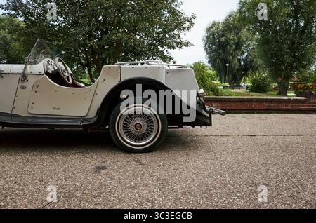 Oldtimer steht auf einer Straße. Das Auto ist weiß und hat ein schwarzes Rad. Das Auto steht vor einem Baum. Pultusk, Polen 20.07.2025 Stockfoto
