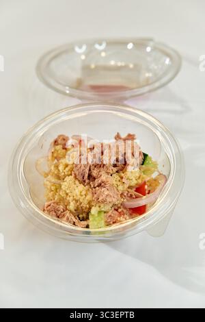Eine frische Portion Couscous Salat mit Thunfisch und buntem Gemüse in einer durchsichtigen Plastikschale für eine gesunde Mahlzeit Option Stockfoto