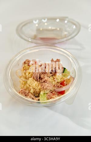 Eine frische Portion Couscous Salat mit Thunfisch und buntem Gemüse in einer durchsichtigen Plastikschale für eine gesunde Mahlzeit Option Stockfoto