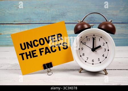 Entdecken Sie den Fakten Text auf Papierkarte mit Wecker auf hölzernem Hintergrund Stockfoto