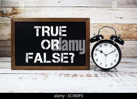 Richtig Oder Falsch? Textnachricht und Wecker auf hölzernem Hintergrund Stockfoto