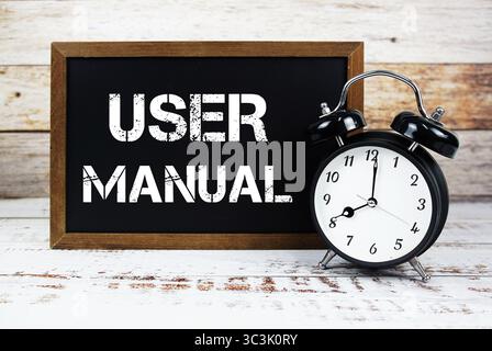Textnachricht und Wecker im Benutzerhandbuch auf hölzernem Hintergrund Stockfoto