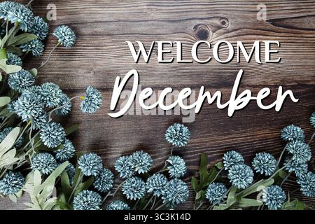 Begrüßungstext im Dezember mit Blumendekoration auf hölzernem Hintergrund Stockfoto