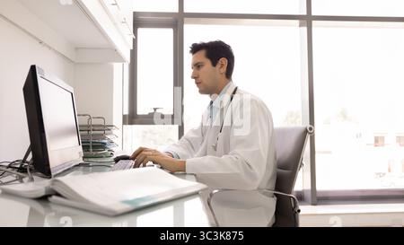 Fokussierter junger Arzt Mann, der am Computer arbeitet Stockfoto