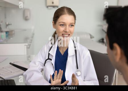 Glückliche junge Ärztin, die mit männlichen Patienten spricht Stockfoto