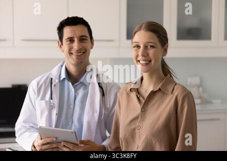 Positiver männlicher Lateinarzt und junge Patientin posieren zusammen Stockfoto