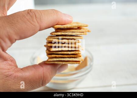 Ein Blick auf eine Hand, die einen Stapel Mandelmehl-Cracker hält. Stockfoto