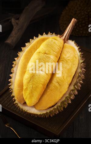 Bild von Durian, köstlichem und frischem vietnamesischem Durian, Durian Fruit Open mit goldenem Fleisch auf dunklem Holztablett Stockfoto