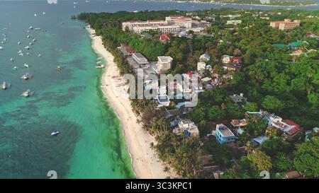 Blick von der Drohne auf den Cagban Beach auf Boracay Island, Philippinen, mit türkisfarbenem Wasser, traditionellen Auslegerbooten, weißem Sand, üppiger tropischer Vegetation und Hotels entlang der Küste Stockfoto