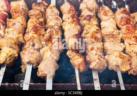 Schweinefleisch wird auf Metallspießen gegrillt. Stockfoto