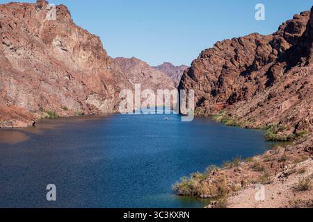 Klares blaues Wasser fließt durch einen Canyon, der von steilen Felsklippen unter hellem Himmel flankiert wird. Stockfoto