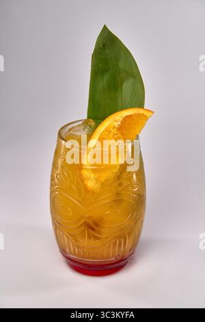 Erfrischender tropischer Cocktail in einem dekorativen Glas, garniert mit Orangenscheibe und Blatt für einen perfekten Sommer-Vibe Stockfoto