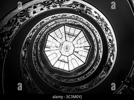 Blick von oben auf die berühmte Bramante-Treppe in den Vatikanischen Museen mit ihrem ikonischen Spiraldesign und Besucher, die die Treppe hinuntergehen. Stockfoto