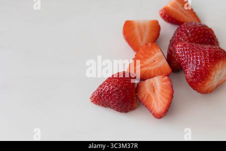 Nahaufnahme von saftigen ganzen und geschnittenen Erdbeeren auf sauberem weißem Hintergrund mit großzügigem Kopierraum. Gesunde Fruchtzusammensetzung ideal Stockfoto