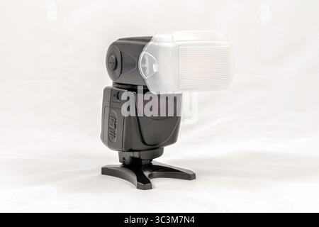 Schräge Ansicht eines schwarzen externen Blitzgeräts ohne Markennamen für DSLR Kamera mit Diffusor angebracht Stockfoto