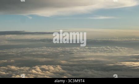 Ein atemberaubender Blick aus der Luft von einem Wolkenmeer während einer wunderschönen goldenen Stunde. Der Himmel ist ein sanftes Blau und schafft eine ruhige und weite Skyline. Stockfoto