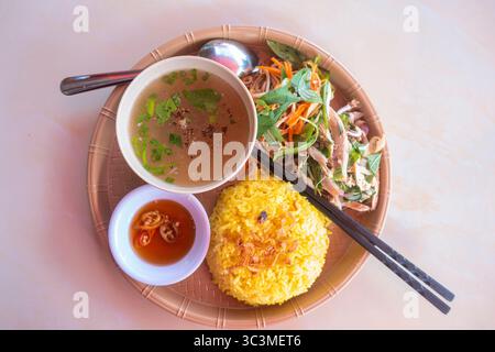 Hühnerreis, ein bekanntes Gericht der Vietnamesen, aus Hühnerbrühe gekocht, gehacktes Hühnchen, serviert mit Gemüse, Karotten, Fischsauce, und Suppe Stockfoto