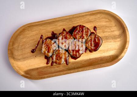 Köstlich gefertigte Sushi Rolls mit herzhafter Sauce auf einem hölzernen Servierteller in einer wunderschönen Präsentation Stockfoto