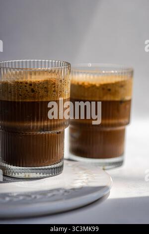 Zwei frostige Cappuccinos in elegantem Glas mit reichhaltigen Schichten Espresso und cremigem Schaum. Perfekt für einen erfrischenden Koffeinschub Stockfoto