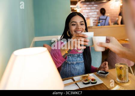Ein Paar, das ein köstliches Sushi-Erlebnis in einem gemütlichen japanischen Restaurant genießt und sorgfältig zubereitete Gerichte genießt, während er einen warmen Toast genießt Stockfoto