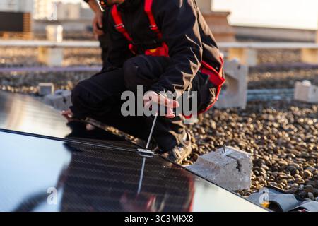 Ein Techniker installiert fachmännisch ein Solarpanel auf einem Dach und betont dabei Lösungen für erneuerbare Energien. Die Szene zeigt moderne Technologie und Son Stockfoto