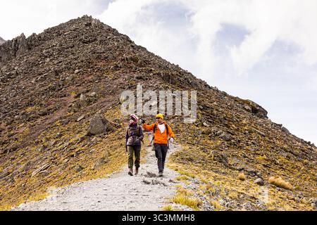 Zwei Wanderer genießen ein aufregendes Abenteuer auf einem malerischen Bergpfad, der ein Gefühl von Freiheit und Erkundung vermittelt. Sie navigieren auf dem zerklüfteten Weg mit en Stockfoto