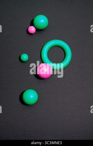 Eine künstlerische Komposition mit geometrischen Formen in Grün und Magenta auf dunklem Hintergrund. Kreisförmige und kugelförmige Formen schaffen eine moderne, minimalistische AE Stockfoto