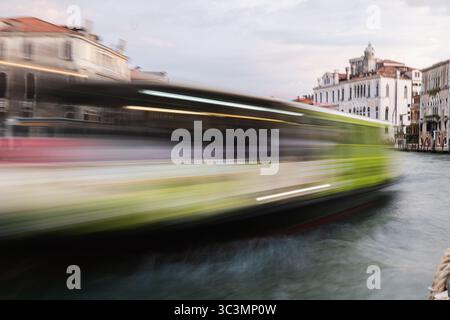 Ein Wassertaxi verschwimmt an historischen Gebäuden am Kanal Venedigs vorbei und zeigt das lebhafte Tempo des täglichen Lebens. Die Bewegung spiegelt den zeitlosen Charme dieser Geschichte wider Stockfoto