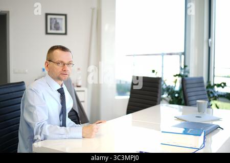 Büroangestellter, der allein im Besprechungsraum sitzt Stockfoto