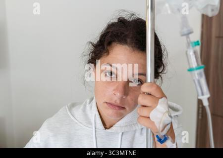 Eine junge Frau liegt in einem Krankenhausbett auf Bali und scheint unwohl. Sie wird medizinisch versorgt und weist auf einen Moment der Verletzlichkeit und Pflege hin Stockfoto