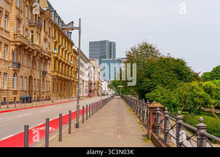 Frankfurt, Deutschland - 10. Juni 2025: Von Bäumen gesäumter Weg mit einer Mischung aus historischen Gebäuden und modernen Wolkenkratzern in Frankfurt, Deutschland Stockfoto